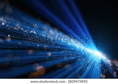 Dynamic abstract visualization of blue light streaks and glowing particles moving rapidly in a dark, futuristic space.