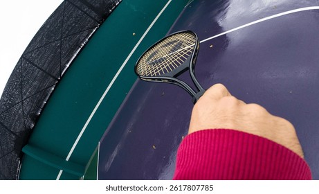 A dynamic action cam angle perspective of a tennis player playing with a racket under a rainy day