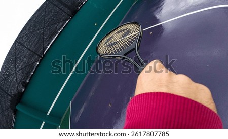 A dynamic action cam angle perspective of a tennis player playing with a racket under a rainy day