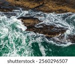 Dynamic aerial view of ocean tidal waves crashing on rocky shores along Vancouver Island