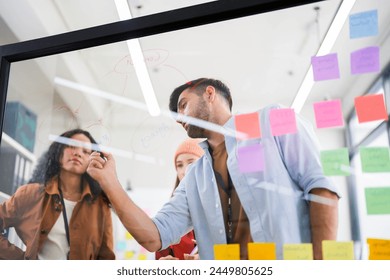 Dynamic brainstorming session with a focused team using a transparent idea board to strategize in the office. - Powered by Shutterstock