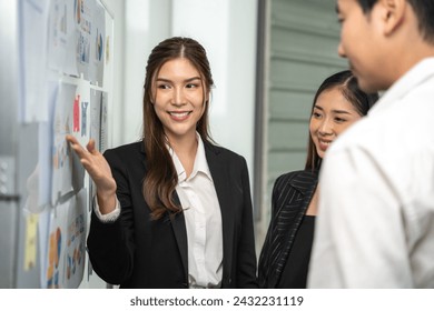 Dynamic businesswoman actively engages with her colleagues, presenting and explaining concepts on a storyboard in a corporate setting. - Powered by Shutterstock