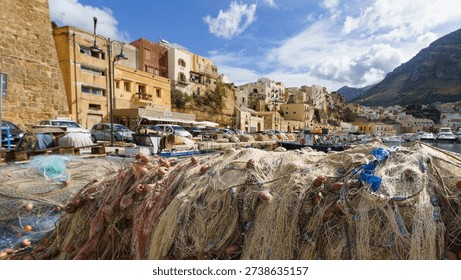 A dynamic, close-up composition capturing moored fishing boats and pleasure craft in the Cala Marina harbor, set against the backdrop of the tightly clustered, colorful historic buildings of Castellammare del Golfos old town, illustrating vibrant Sicilian maritime life and authentic port charm.