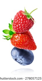 Dynamic composition of flying fresh berries. Levitating strawberry, blueberry, and raspberry with green leaves on a white background.