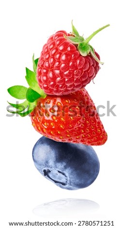 Dynamic composition of flying fresh berries. Levitating strawberry, blueberry, and raspberry with green leaves on a white background.