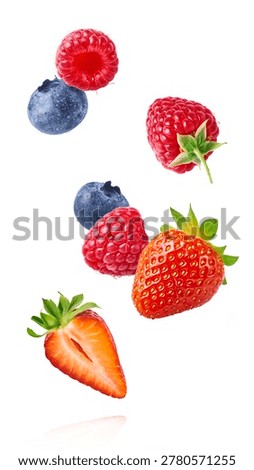 Dynamic composition of flying fresh berries. Levitating strawberry, blueberry, and raspberry with green leaves on a white background.