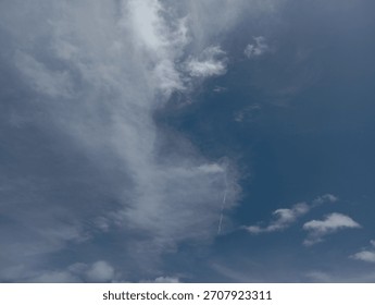 A dynamic composition of white, fluffy cumulus clouds floating high in the expansive, soft blue summer sky