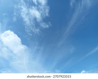 A dynamic composition of white, fluffy cumulus clouds floating high in the expansive, soft blue summer sky