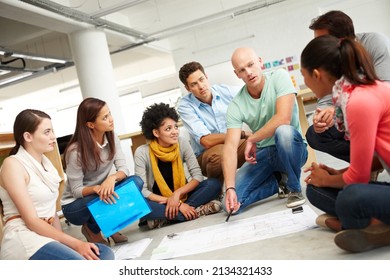 Dynamic designers. A group of multi-ethnic creatives huddled together and listening to the presentation of a plan. - Shutterstock ID 2134321433