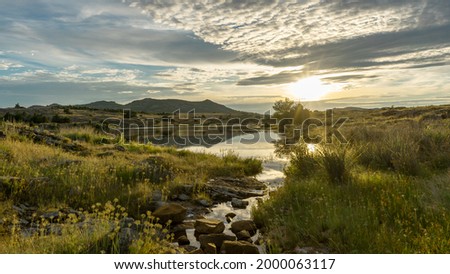 A dynamic evening sky over a small pond.
