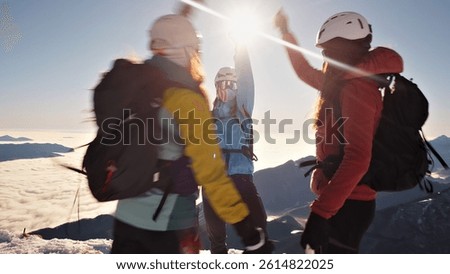 A dynamic, fast-paced camera shot captures three hikers on a snowy peak, exuding team spirit and relaxation as they celebrate their achievement.