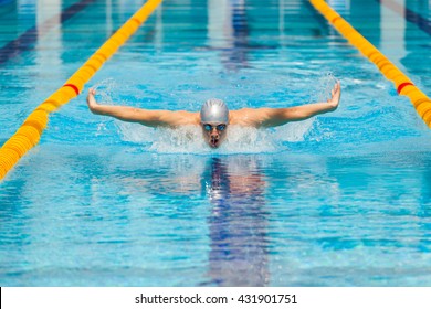 dynamic and fit swimmer in cap breathing performing the butterfly stroke - Powered by Shutterstock