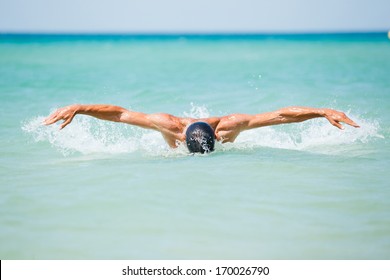 Dynamic and fit swimmer man swimming the butterfly stroke in ocean