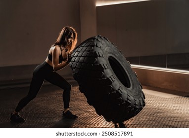 In a dynamic gym setting, a strong woman engages in rigorous training, showcasing her impressive tire flip technique. This exercise epitomizes her dedication to fitness and strength improvement - Powered by Shutterstock