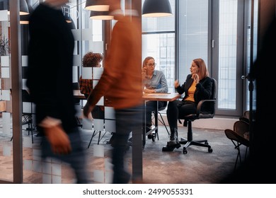 In the dynamic hustle and bustle of a business environment, a group of young business professionals walk down the corridor next to their office, while their colleagues collaborate inside, symbolizing - Powered by Shutterstock