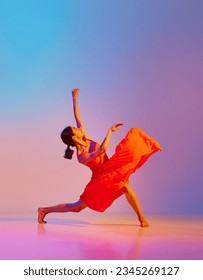 Dynamic image of artistic young woman dancing in elegant red dress against gradient multicolor background in neon light. Concept of modern dance style, hobby, art, performance, lifestyle, ad - Shutterstock ID 2345269127