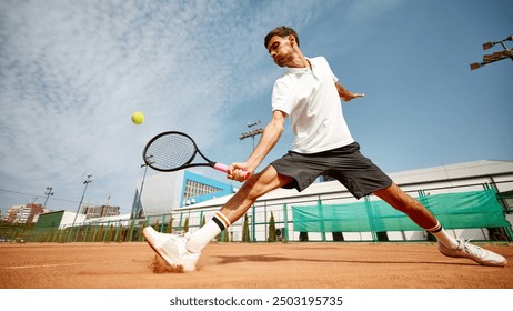 Dynamic image of focused young man in white t-shirt playing tennis on outdoor clay court, showing energy and focus during match. Concept of sport, competition, active and healthy lifestyle - Powered by Shutterstock