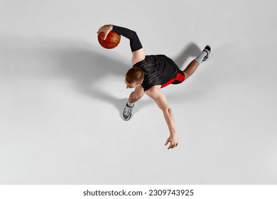 Dynamic image of professional sportsman, basketball player in motion with ball during game against grey studio background. Top view. Concept of professional sport, hobby, healthy lifestyle, action - Powered by Shutterstock