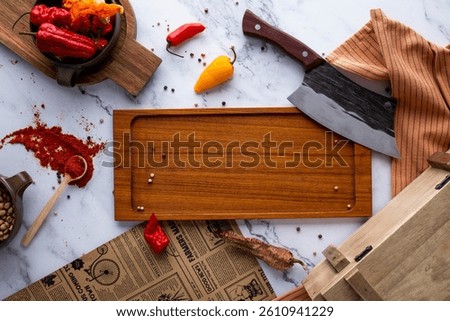 A dynamic kitchen prep scene filled with chili peppers, spices, and culinary tools. The wooden chopping board and large knife suggest a spicy cooking session, surrounded by a dash of hot sauce.