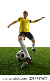 Dynamic low angle view of young man, soccer player controlling ball, stabilizing stance, preparing for next move during match and training session against white background. Concept of game, sport