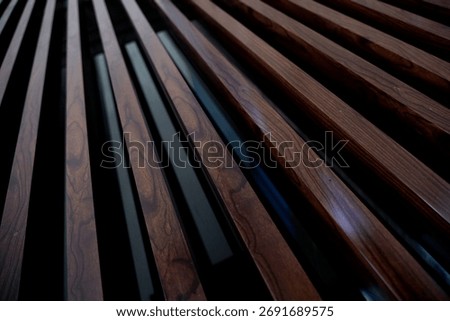 Dynamic low-angle perspective of dark brown fluted wood paneling. Close-up of rich wood grain texture. Abstract background