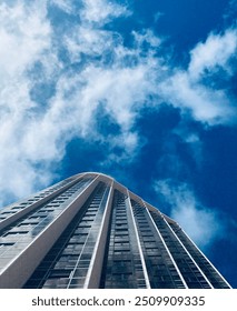 Dynamic low-angle shot of a towering building against the sky, showcasing modern architecture and urban design. Perfect for themes of construction, cityscape, skyscrapers, and urban development