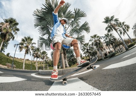 Dynamic low-angle shot of a young man doing a skateboard trick on a tropical street with palm trees. Urban energy meets laid-back coastal vibe.