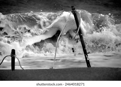 The dynamic motion of ocean waves crashing against wooden poles tied with ropes - Powered by Shutterstock