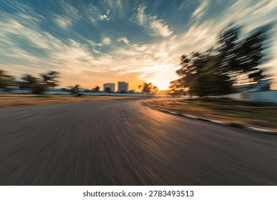 A dynamic, motion-blurred view of a sunset casting golden light over a distant cityscape, with silhouetted trees framing the scene.