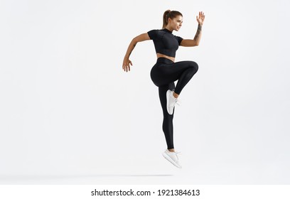 Dynamic movement of young and healthy sports woman doing jump exercising in sportswear. Fitness female in sport costume raising leg, running on white background. - Powered by Shutterstock