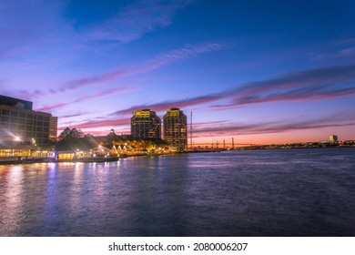 A dynamic night view of bustling Halifax Waterfront Harbor front with prominent business and financial buildings and restaurants with the MacDonald Bridge at background, Nova Scotia, Canada. 