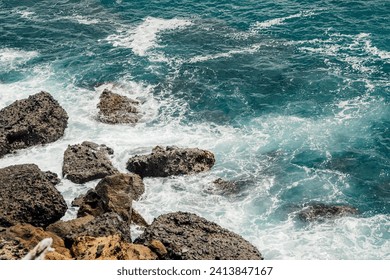 Dynamic ocean waves hitting jagged coastal rocks