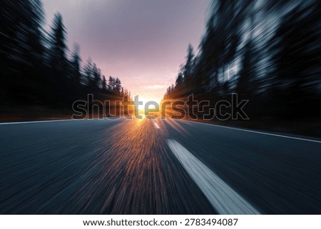 A dynamic perspective of a road stretching towards a brilliant sunset, with trees blurring on either side and a strong lens flare effect.