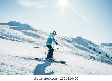 Dynamic picture of woman skier in blue outfit on the piste ski downhill fast motion in Alps. Active winter holidays, skiing downhill in overcast day. Ski rides on the track with swirls of fresh snow