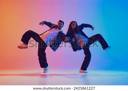 Dynamic portrait of dance duo, talented man and woman in dance poses against gradient studio background in neon light, filter. Concept of youth culture, music, lifestyle, hobby, action. Gel portrait.