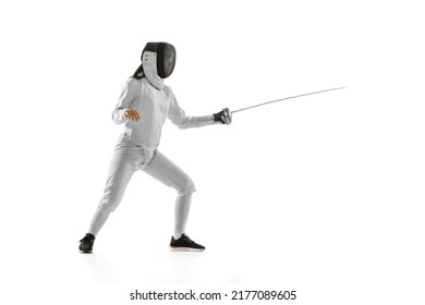 Dynamic Portrait Of Female Fencer In Sports Costume And Fencing Mask Holding Rapier In Hand And Training Isolated On White Background. Sport, Youth, Healthy Lifestyle, Achievements. Copy Space For Ad