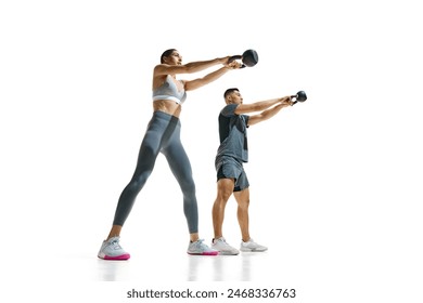 Dynamic portrait of fit man and woman performing kettlebell squat exercise against white studio background. Concept of people in sport, healthy lifestyle, teamwork, motivation. Ad - Powered by Shutterstock