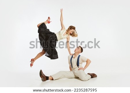 Dynamic portrait of happy, stylish and energetic dancers dancing lindy hop or swing dance isolated on white background. Concept of music, energy, happiness, mood, action, style