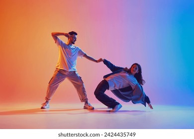 dynamic portrait of man and woman dancing in pair in motion against gradient studio background in neon light, filter. Performance. Concept of youth culture, music, lifestyle, action. Gel portrait. - Powered by Shutterstock