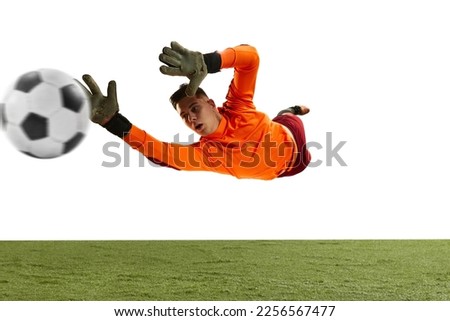 Dynamic portrait of professional soccer goalkeeper in sports uniform jumping and catching football ball isolated over white background. Concept of sport, action, motion, goals. Wide angle view