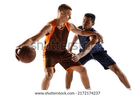 Dynamic portrait of two men, professional basketball player training isolated over white studio background. Possession of the ball. Concept of sport, action, team game, active lifestyle