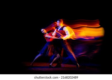 Dynamic portrait of young ballroom dancers dancing Argentine tango isolated on dark background with neon mixed light. Concept of art, beauty, grace, action, emotions. Copy space for ad