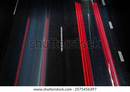Dynamic red light trails on a dark urban highway, showcasing motion, speed, and the energy of city nightlife