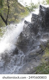 Dynamic and Refreshing Mountain Waterfall Cascading Down Rocky Terrain Surrounded by Lush Greenery - A Natural Backdrop for Serenity and Adventure