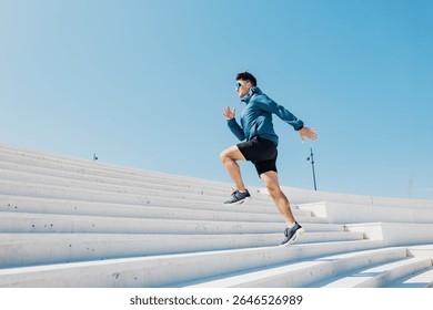 Dynamic runner ascends outdoor steps under bright blue sky, showcasing athleticism and determination during a sunny afternoon workout session