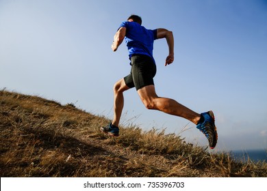 dynamic running uphill on trail male athlete runner side view