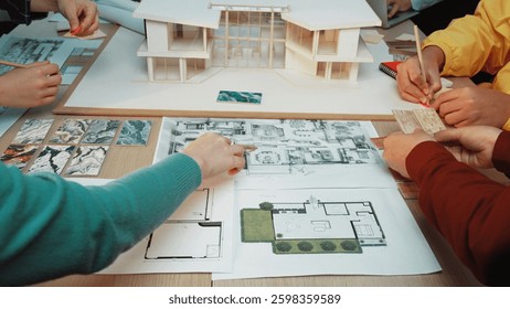 A dynamic scene of a collaborative design session where individuals engage with architectural models and planning documents, showcasing creative teamwork in modern design processes. SACTR