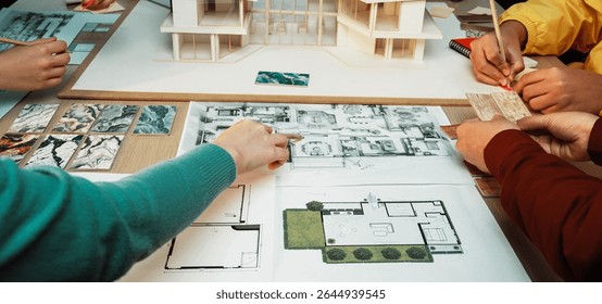 A dynamic scene of a collaborative design session where individuals engage with architectural models and planning documents, showcasing creative teamwork in modern design processes. SACTR