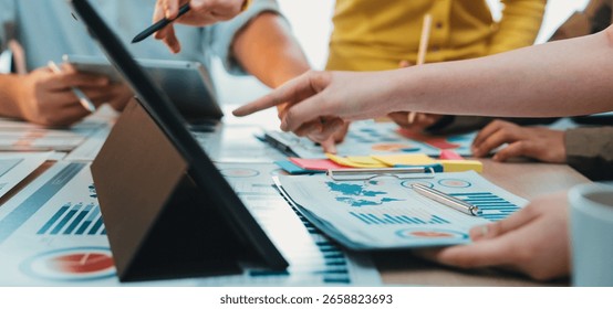 A dynamic scene of a collaborative meeting showcasing diverse hands engaged in discussion over data charts and digital devices in a modern office setting. SACTR