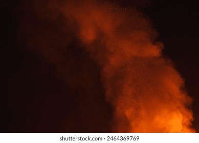 Dynamic scene of large fire at night in a desert setting. Bright orange flames contrast with dark smoke, creating a striking visual display in the dark sky.